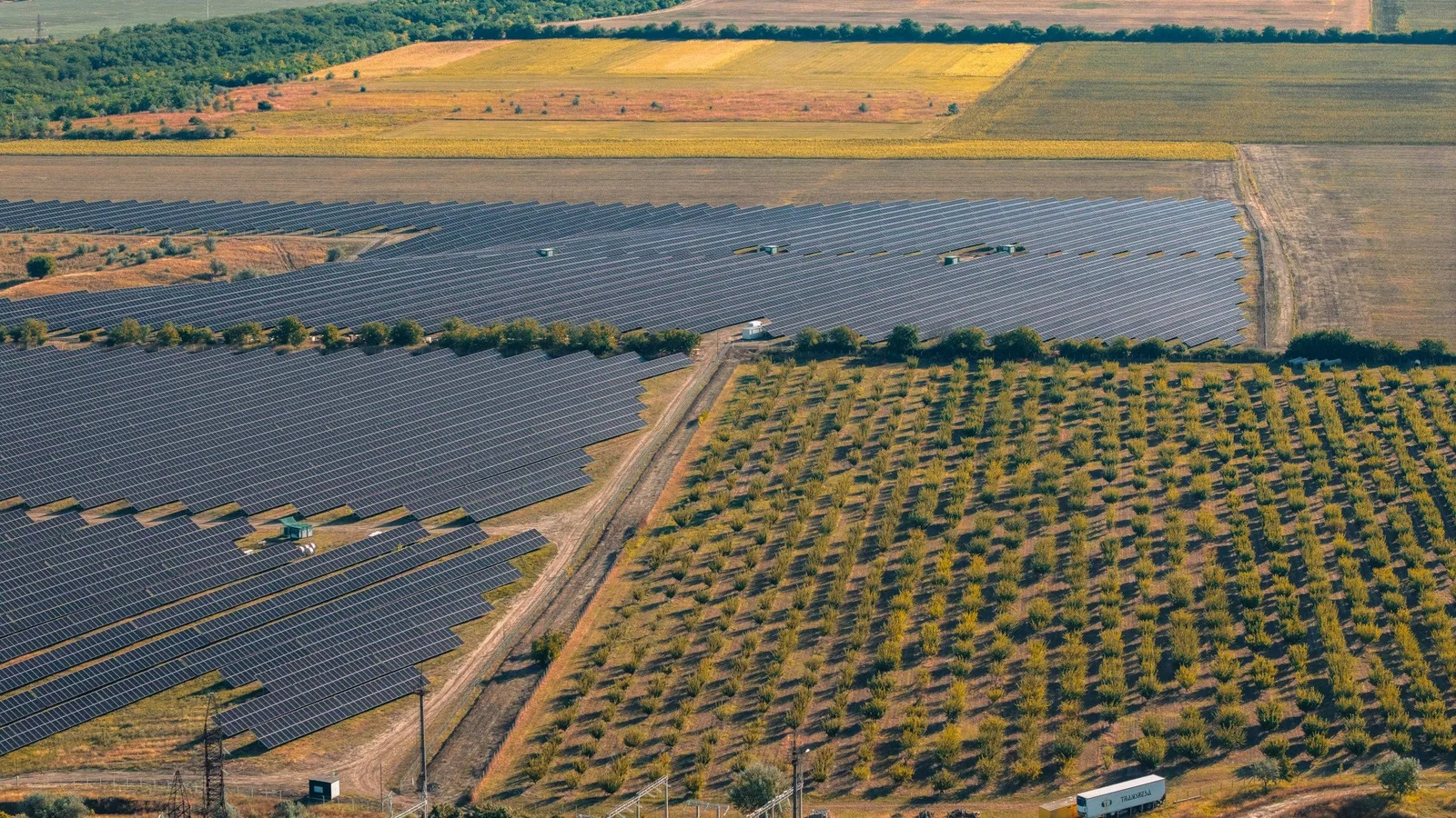 Luftaufnahme eines großen Solarparks zwischen Feldern und Obstplantagen